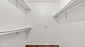 A small, white-walled room with wooden flooring, two white shelves, and a white door. - World Cup Walkable | King Bed Retreat (Arlington)