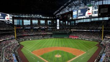 A large stadium with multiple tiers of seating, a central field, and large digital displays.
