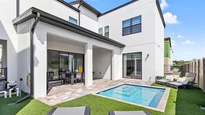 Una casa moderna con piscina, mobiliario exterior y zona de patio.