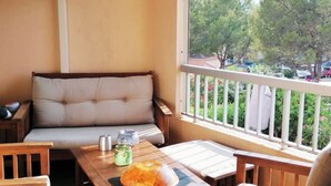 Een balkon met een comfortabele bank, een tafel met een brood, een glas water en een kaars.