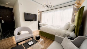 A modern hotel room with a large bed, a flat-screen TV, a vanity with a sink, and a green accent wall. - Mount Alverno Luxury Resorts (Caledon)