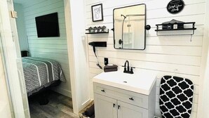 Un dormitorio compacto con cama, tocador pequeño con espejo y un perchero para toallas.