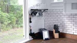 Una cocina moderna con armarios blancos, encimera de madera, microondas integrado y ventana con vistas a zonas verdes.