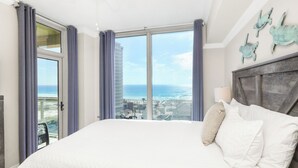 A spacious bedroom with a large bed, a view of the ocean, and a balcony. - New Listing P2-1106 2B Gulf View at Portofino! (Pensacola Beach)