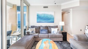 A modern living room with a sectional sofa, a coffee table, and a ceiling fan. - New Listing P2-1106 2B Gulf View at Portofino! (Pensacola Beach)