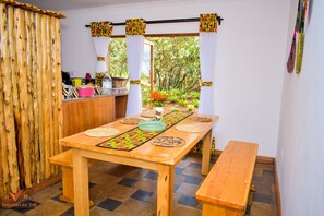 Enjoy meals in this cozy dining area with a table for two, a bench, and a view of lush greenery.