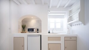 A modern kitchen with a microwave, sink, and cabinets. - Pietra Bianca 1891 Suites Mykonos (Mykonos)