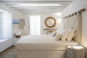 Una camera da letto con un letto grande, un comodino, uno specchio appeso al muro e una finestra vista spiaggia.