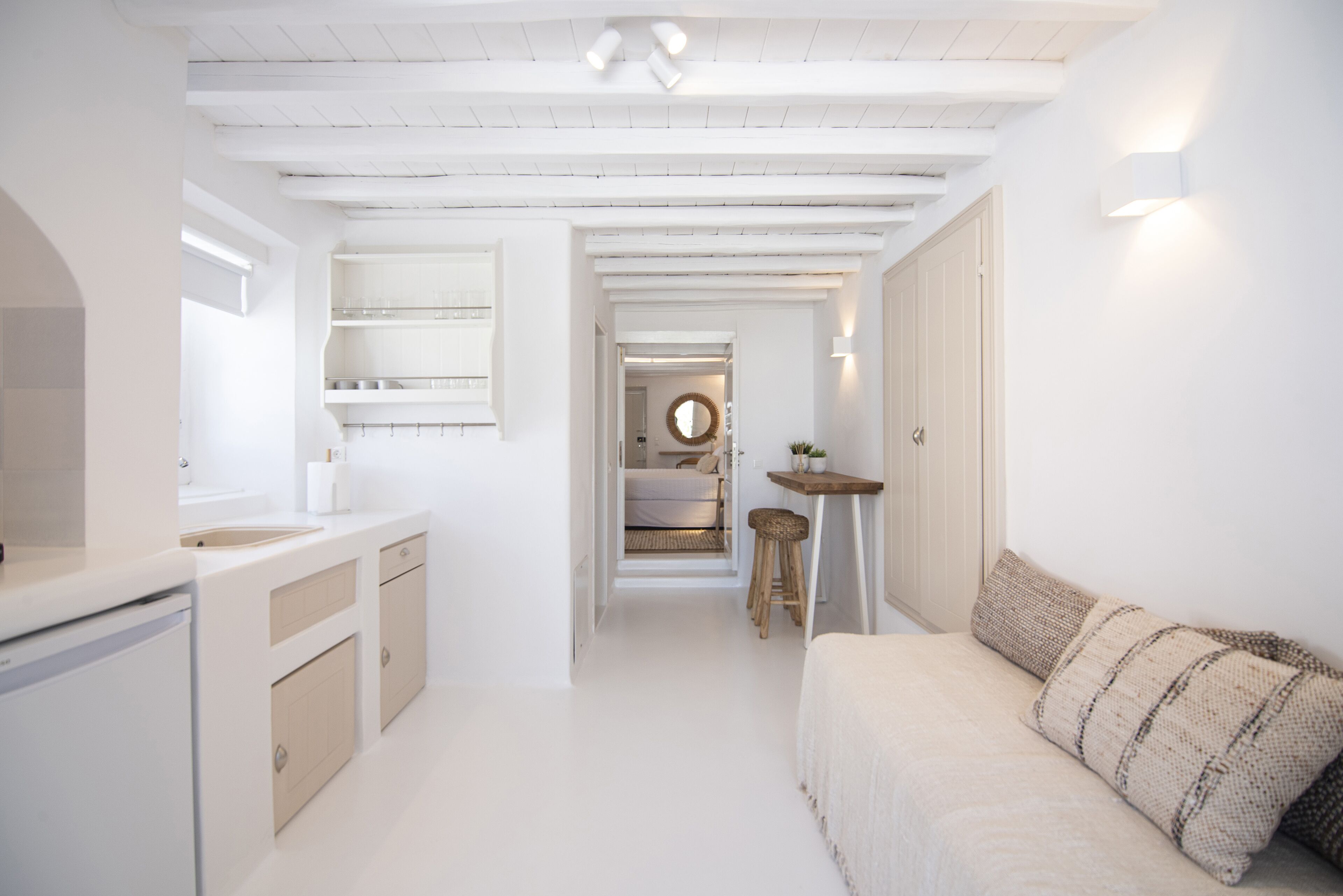 A modern, minimalist kitchen with white cabinetry and a built-in oven.