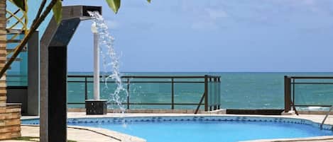 Una piscina al aire libre, sombrillas, sillones reclinables de piscina