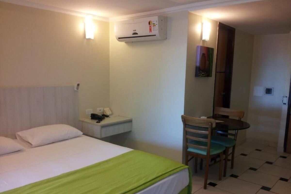 A hotel room with a bed, a desk, a chair, and a small table.