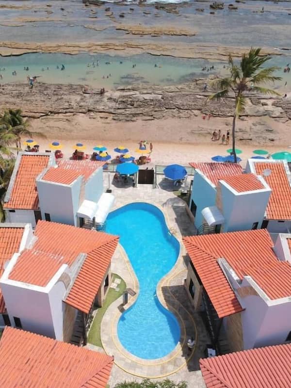 Una piscina al aire libre, sombrillas, sillones reclinables de piscina