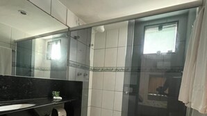 A modern bathroom with a glass shower enclosure, a black countertop, a white toilet, and a large mirror. - Hotel Arrecife dos Corais (Cabo de Santo Agostinho)