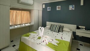 A hotel room with a bed, a window with curtains, an air conditioning unit, and a bedside table. - Hotel Arrecife dos Corais (Cabo de Santo Agostinho)
