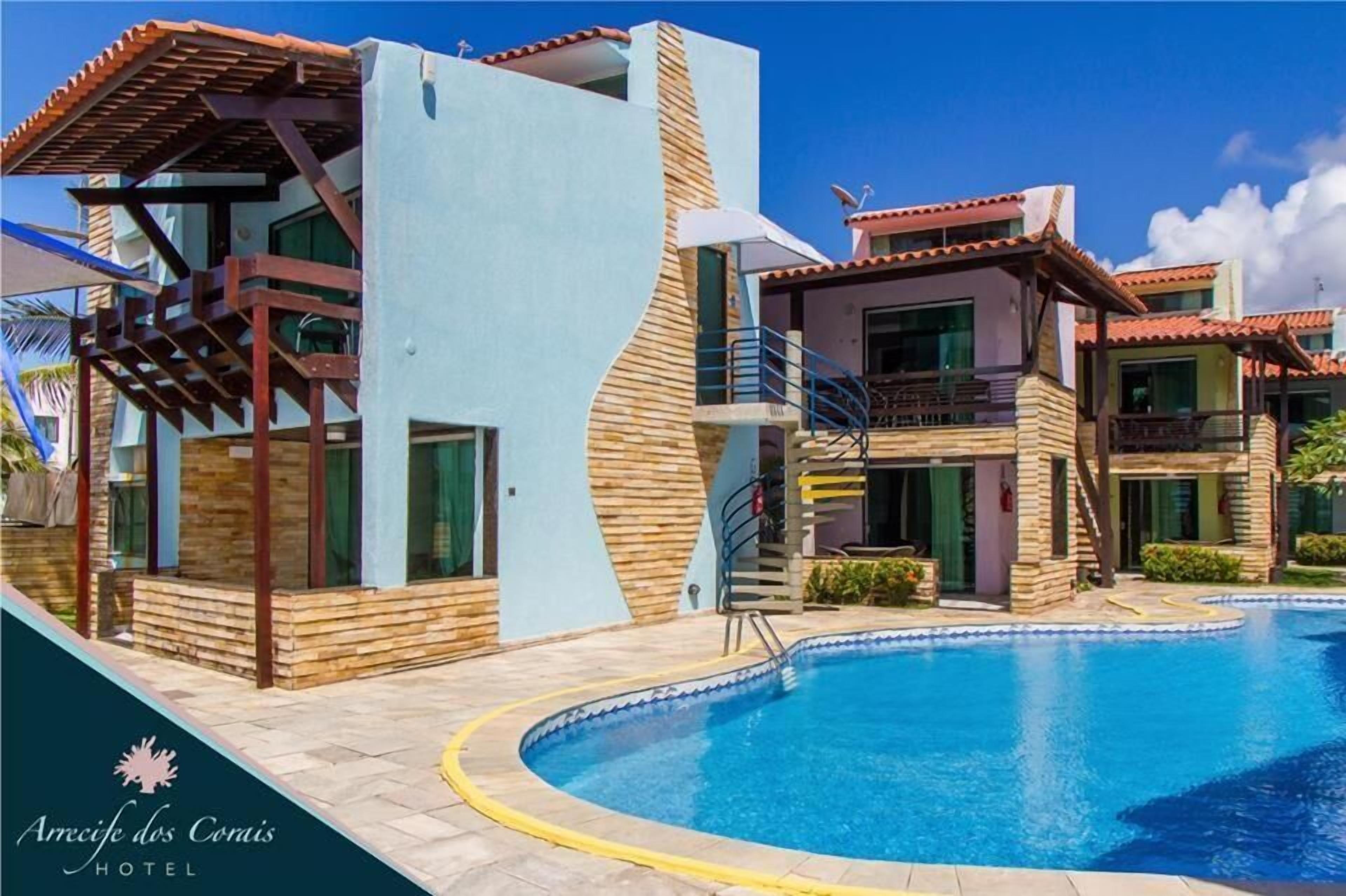 A modern hotel with a pool, featuring a unique architectural design with wooden accents and a light blue facade.
