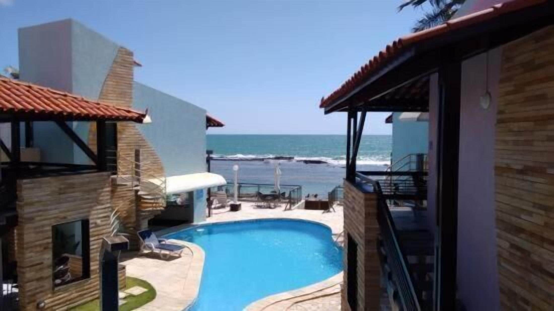 A pool area with a view of the ocean, surrounded by buildings with a modern architectural style.