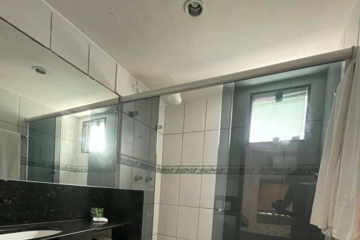 A bathroom with a toilet, a sink with a mirror, a shower with glass doors, and a window.