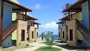 A resort with multiple buildings featuring wooden balconies and a central pathway leading to the ocean. - Hotel Arrecife dos Corais (Cabo de Santo Agostinho)