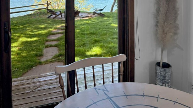 A room with a view of a lake, a dining table, and a hanging light fixture.
