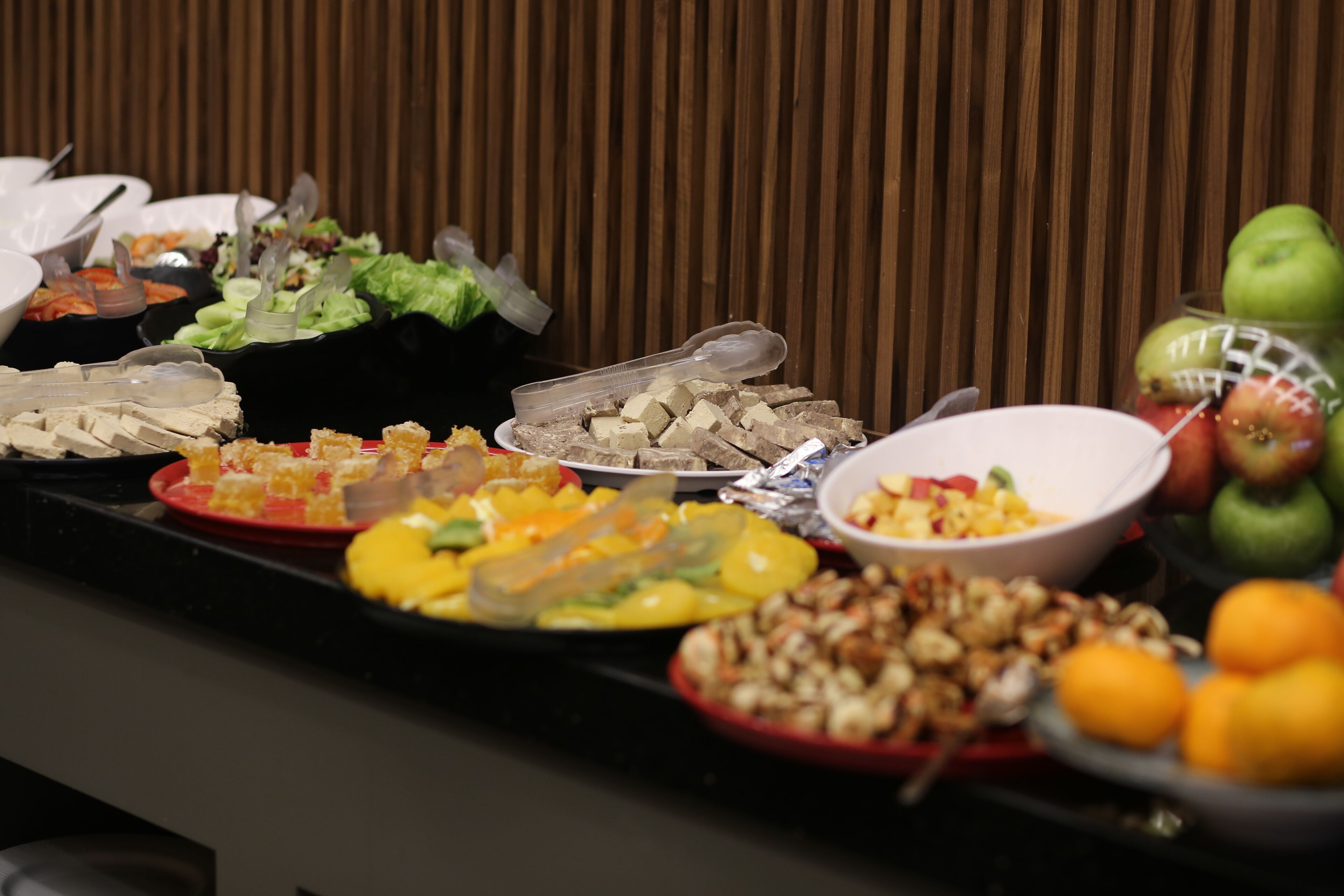 A buffet table with various dishes and fruits.