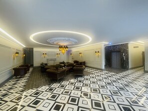 A lobby with a patterned floor, a chandelier, and seating areas. - Lala Grand Hotel (Erzurum)