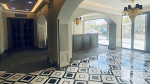 Un vestíbulo amplio con piso de diseño geométrico, grandes puertas en arco y un candelabro.