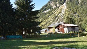 Eine rustikale Holzhütte mit Steinunterbau, umgeben von einer Rasenfläche und einem Holzzaun.
