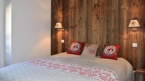 Ein Schlafzimmer mit einer Holzwand, zwei Nachttischlampen und drei Kissen mit rotem und weißem Muster.