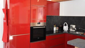 Eine Küche mit roten Schränken, einem schwarzen Backofen und einer Kaffeemaschine.