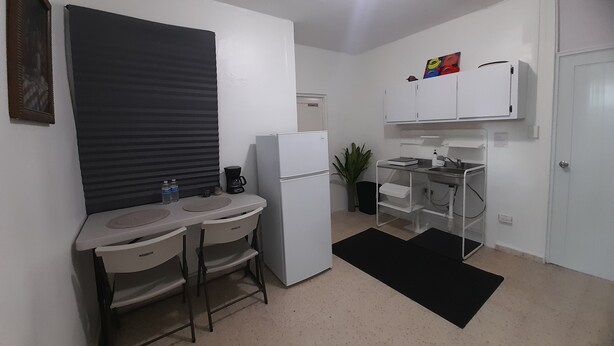 A compact kitchen with a refrigerator, a coffee maker, and a sink.
