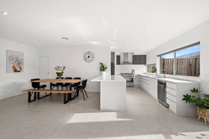 Una cocina moderna con una isla central, un comedor con mesa de madera y un amplio ventanal con vistas.
