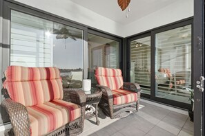 A balcony with wicker furniture and a glass door.