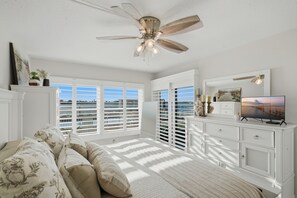 A room with a ceiling fan, a television on a dresser, and large windows with blinds. - Breathtaking Panoramic Ocean views and quick drive or walk to Pass A Grill Beach (St. Petersburg)