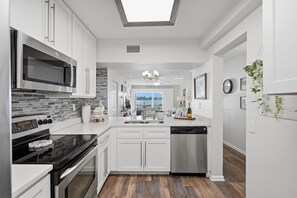 A modern kitchen with white cabinetry, a black stove, and a dishwasher. - Breathtaking Panoramic Ocean views and quick drive or walk to Pass A Grill Beach (St. Petersburg)