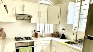 A modern kitchen with white cabinets, a gas stove, a sink, and a window providing natural light. - Beautiful apartment in downtown Polanco (Ciudad de México)