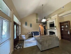 Relax in this inviting living room with a fireplace, sofa, armchairs, and a bookshelf.