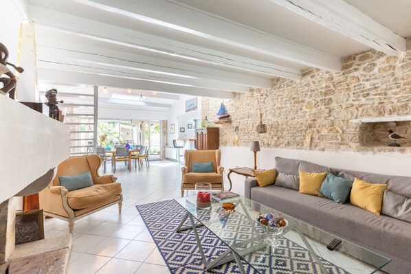 A spacious living area with a stone wall, a sofa with cushions, a glass coffee table, and a patterned rug.