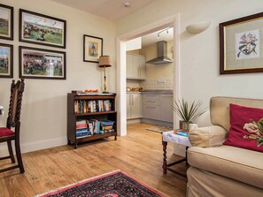 A cozy living room with a wooden floor, a sofa, a bookshelf, and framed pictures on the wall. - 1 bedroom accommodation in Kelso (Kelso)