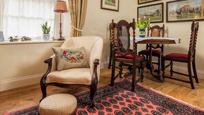 A traditional room with a wooden chair, a table with a vase of tulips, and framed historical paintings on the wall. - 1 bedroom accommodation in Kelso (Kelso)