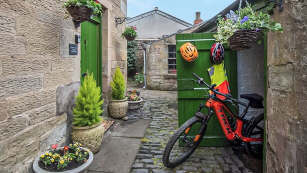 A narrow cobblestone alley with a green door, a bicycle, and a helmet hanging on the door. - 1 bedroom accommodation in Kelso (Kelso)