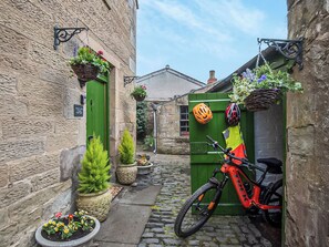 A narrow cobblestone alley with a green door, a bicycle, and a helmet hanging on the door. - 1 bedroom accommodation in Kelso (Kelso)
