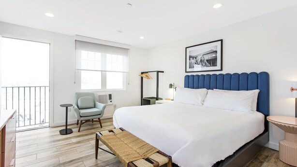 Ein modernes Hotelzimmer mit einem großen Bett, einer Sitzecke mit einer Bank, einem kleinen Tisch und einem Stuhl.