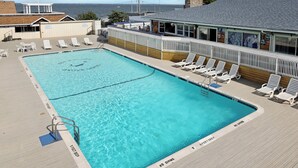 Ein rechteckiger Pool mit Holzterrasse, Liegestühlen und einem Rettungsschwimmerstand.