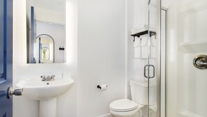 Ein modernes Badezimmer mit weißem Waschbecken, WC und Duschkabine aus Glas.