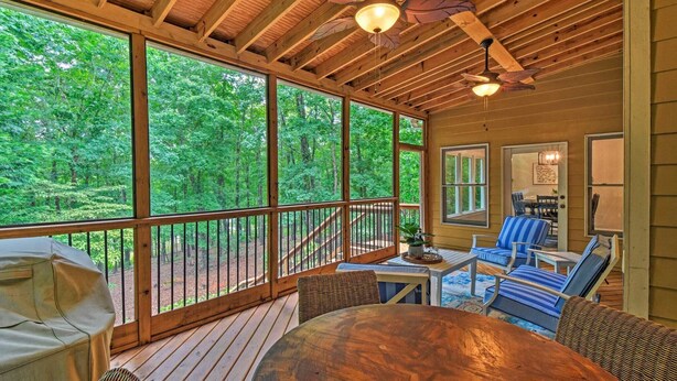 A wooden deck with a view of a forest, a ceiling fan, and outdoor furniture. - Lakefront family home w/ private 2-story dock & NEW outdoor deck for dining! (Dawsonville)