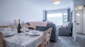 Ein Essbereich mit Tisch für zwei Personen, einer Couch und einem Relaxsessel.
