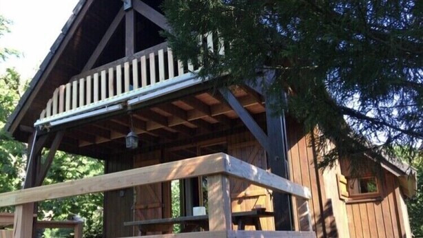 A wooden cabin with a porch and a covered picnic table.
