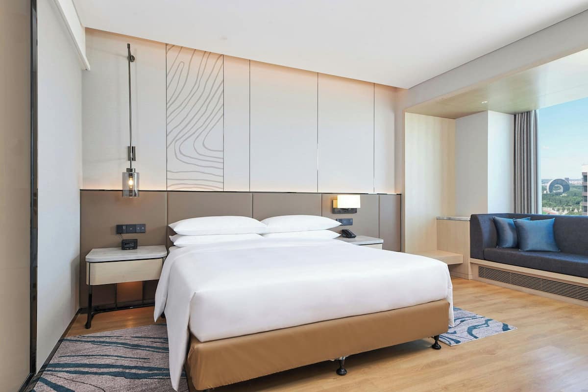 Ein modernes Hotelzimmer mit einem großen Bett, Nachttischen, einem Schreibtisch und einer Couch.
