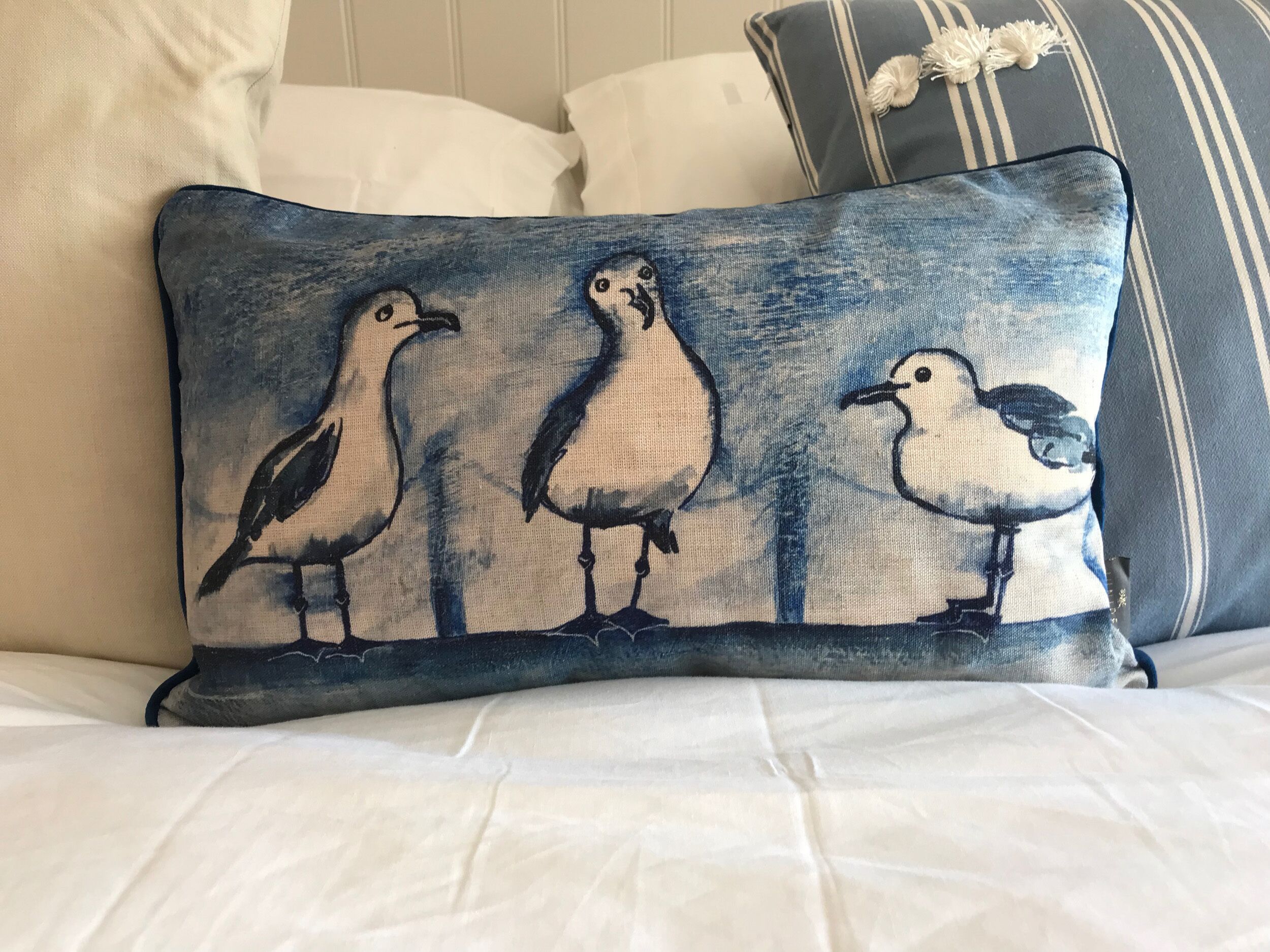 A pillow with a bird design on a bed.