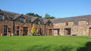 Un edificio de piedra con varias habitaciones y un patio cubierto de césped.